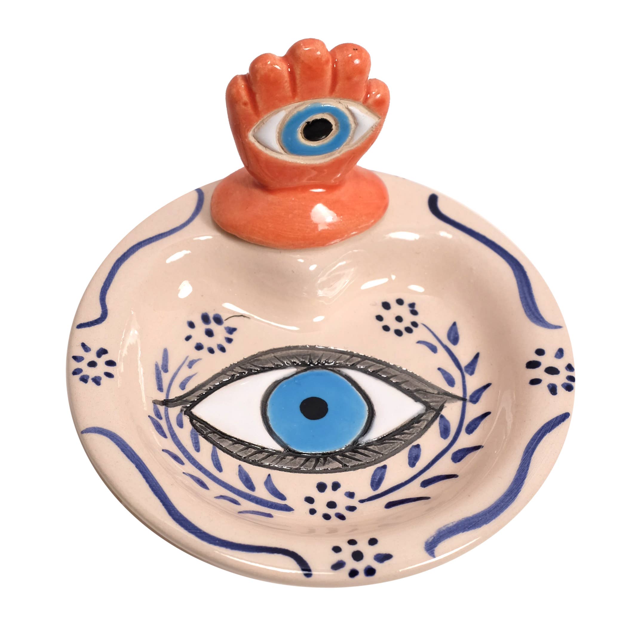 Ceramic dish with eye design and hand holding an eye on top, on a white background